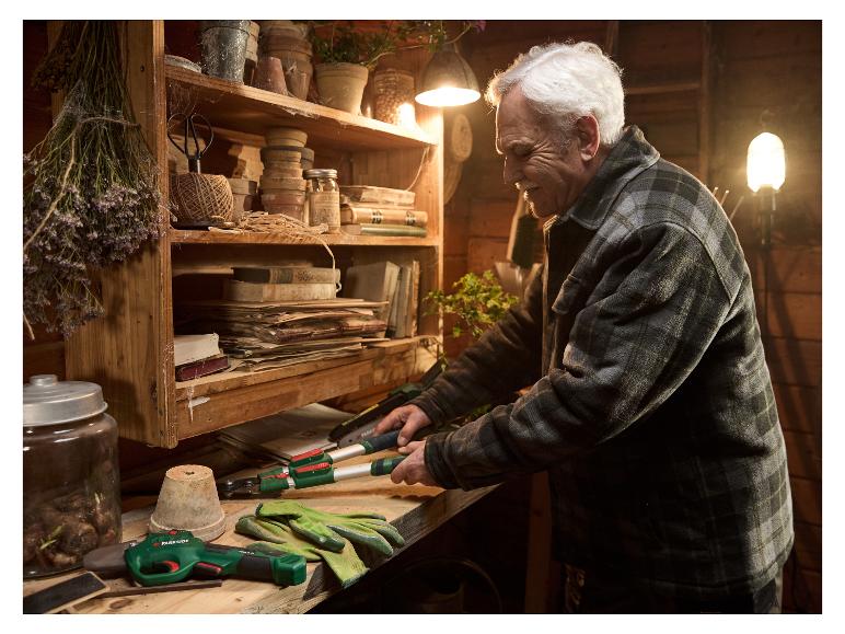 Een oudere man gebruikt Parkside tuingereedschap in zijn rustieke werkplaats.