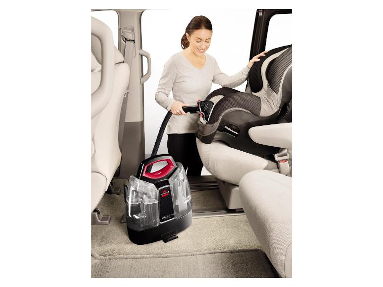 Vrouw reinigt een autostoel in een auto met een Bissell MultiClean vlekkenreiniger.