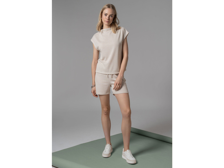 Vrouw in een beige top en korte broek met witte sneakers