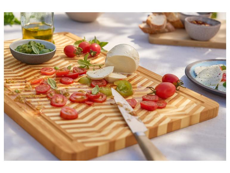 Mozzarella, cherrytomaatjes en pesto op een bamboe snijplank.