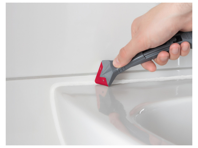 Een hand die een siliconenkitspatel gebruikt om kit aan te brengen tussen tegels.