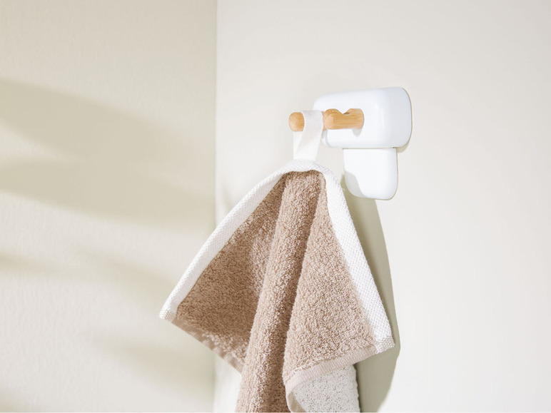 Een beige handdoek hangt aan een witte haak met houten handvatten.