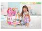 Meisje speelt met BABY born pop en kledingrek met poppenkleding.