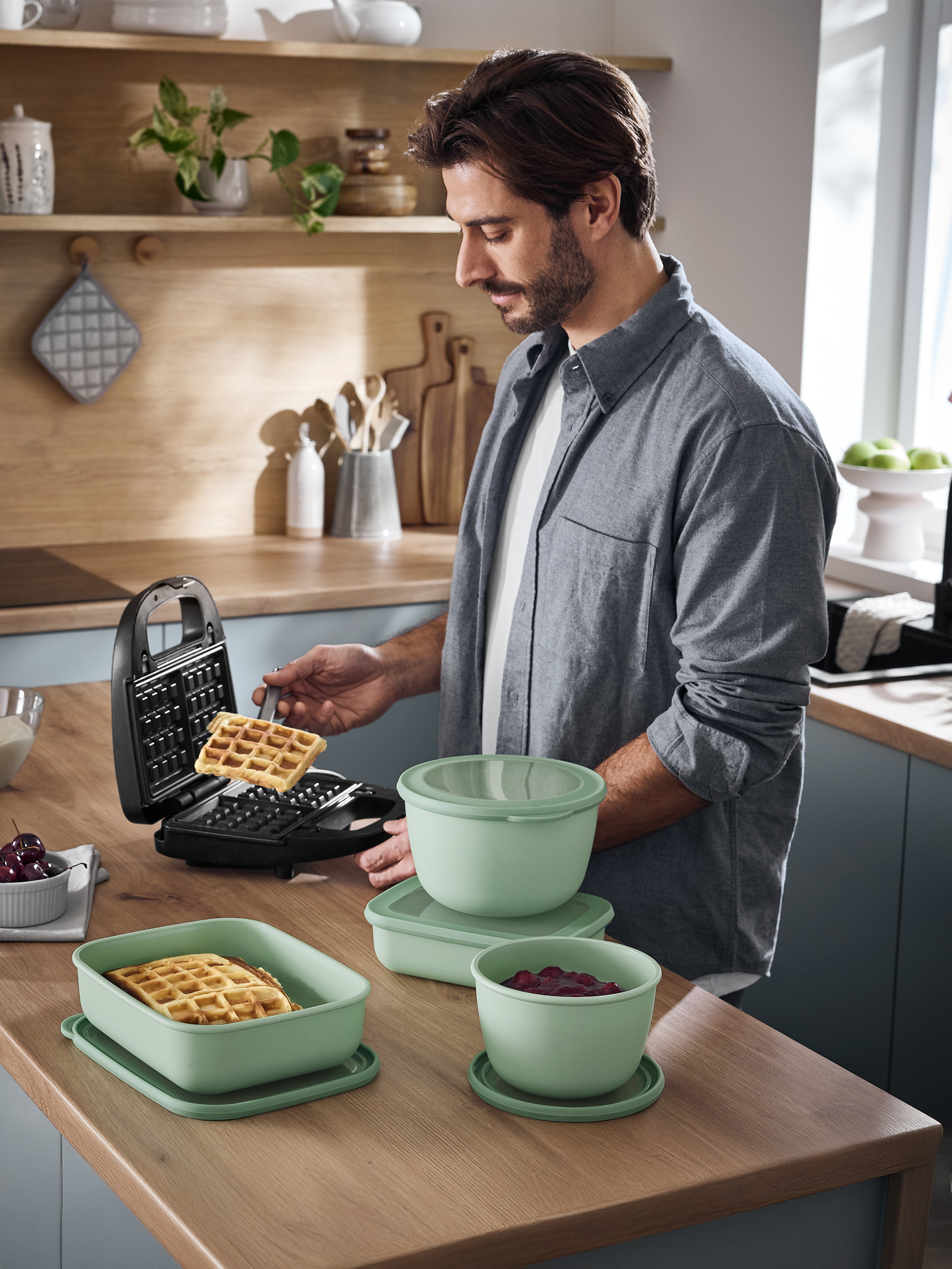 Man maakt wafels met een wafelijzer en serveert ze in groene voedselcontainers.
