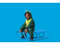 Jongen in groen skipak zit op een blauwe slee.