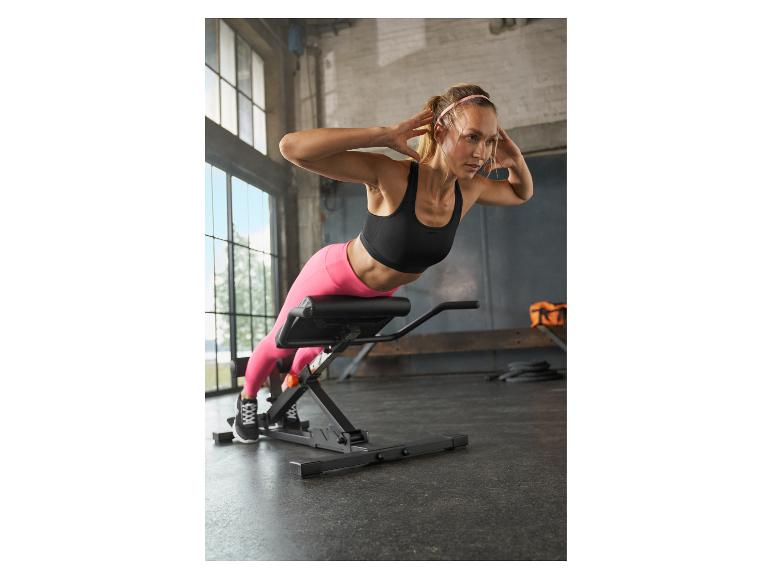 Vrouw op een hyperextensiebank die een rugoefening doet in een sportschool.