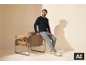 Man in een zwart shirt met lange mouwen en grijze joggingbroek zittend op een fauteuil.