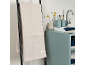Beige badhanddoek op zwarte ladder, met wastafel en badkameraccessoires.