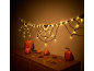 Halloween decoraties met verlicht spinnenweb en pompoenen op een houten kast.