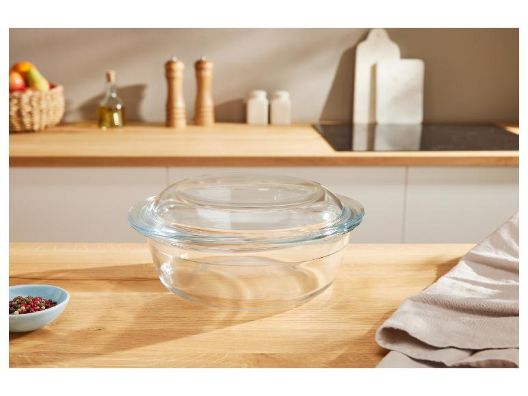 Een glazen schaal met deksel op een houten aanrecht in een lichte keuken.