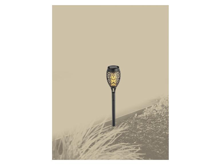 Solar tuinlamp met vlameffect in een bloembed.