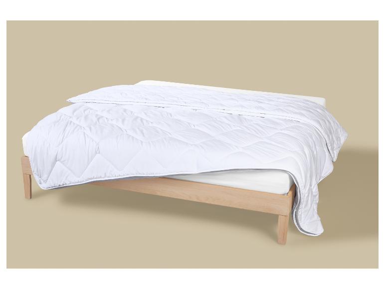 Wit dekbed op een licht houten bed