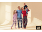 Gelukkige familie in bijpassende geruite pyjama's, moeder houdt baby vast.