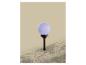 Op zonne-energie werkende tuinlamp met paarse bol, verlicht een tuinperk.