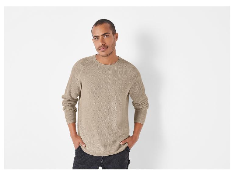 Man draagt ​​een beige gebreide trui met lange mouwen.