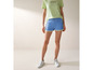 Vrouw draagt blauwe shorts met witte sneakers en een lichtgroen T-shirt van US Grand Polo.