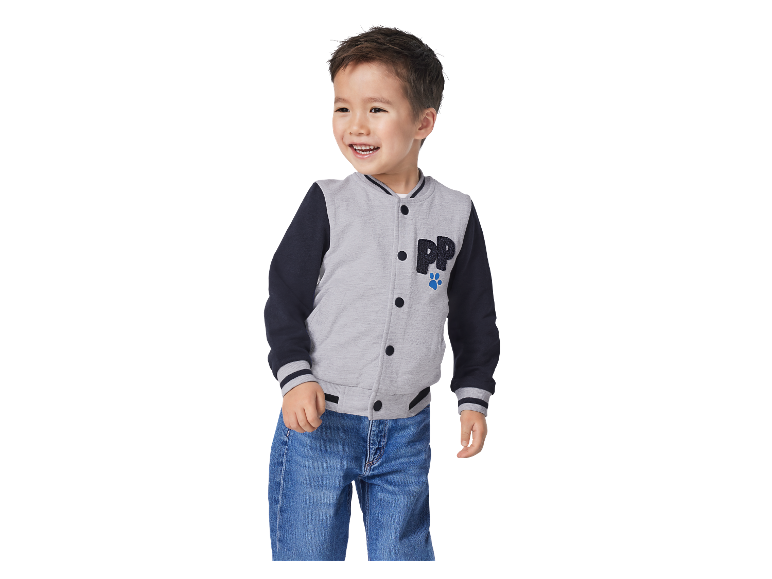 Lachende jongen in een grijze en donkerblauwe Paw Patrol baseballjas.