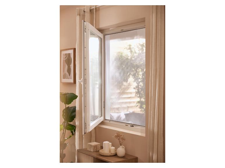 Open raam met gordijnen, plant en decoraties op een bijzettafel.