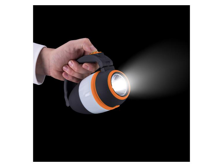 Hand houdt een zwarte en oranje zaklamp met een heldere lichtstraal vast.