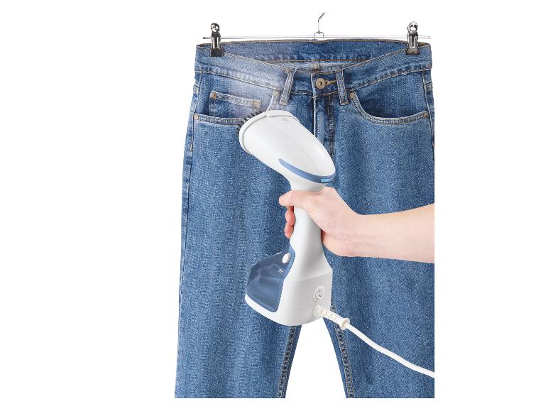 Een stoomstrijkijzer in gebruik op een spijkerbroek.