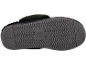 Zool van een zwarte pantoffel met een golvend patroon en een cirkelvormig logo.