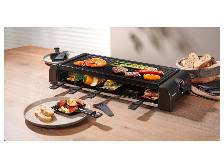 Raclette grill op tafel met garnalen, vlees, groenten en brood.