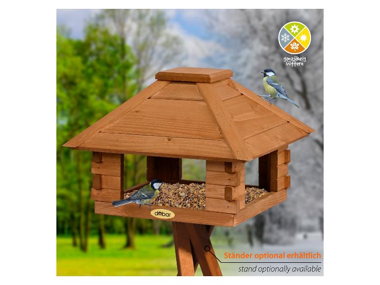 Houten vogelvoederhuisje met twee koolmezen, vogelvoer en tekst 'ganzjährig füttern'.