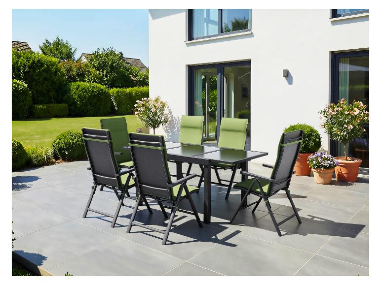 Terras eethoek met zwarte tafel en zes stoelen met groene kussens op een betegeld terras.