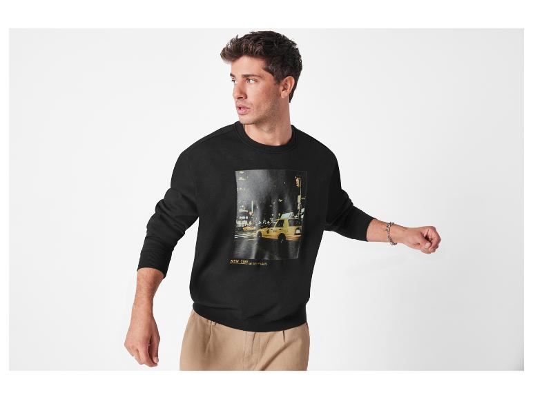 Een jonge man draagt een zwart sweatshirt met een print van een New Yorkse taxi.