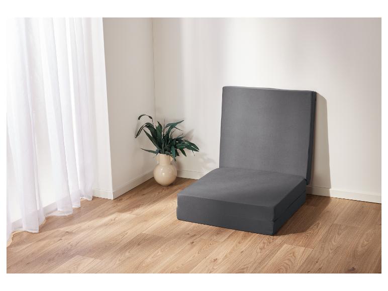 Grijze opklapbare matras in een lichte kamer.