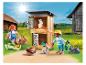 Playmobil figuren van kinderen die konijnen voeren in een hok op een boerderij.