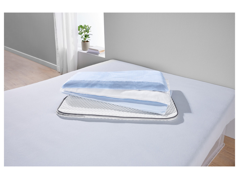 Een blauwe hoeslaken en kussens op een bed.