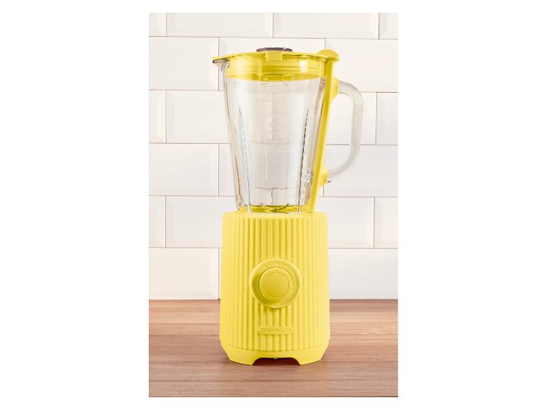 Gele SILVERCREST blender met glazen kan, op een houten aanrecht en witte tegels.