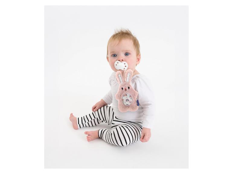 Baby met speen en roze pluche konijn, zittend op witte achtergrond.