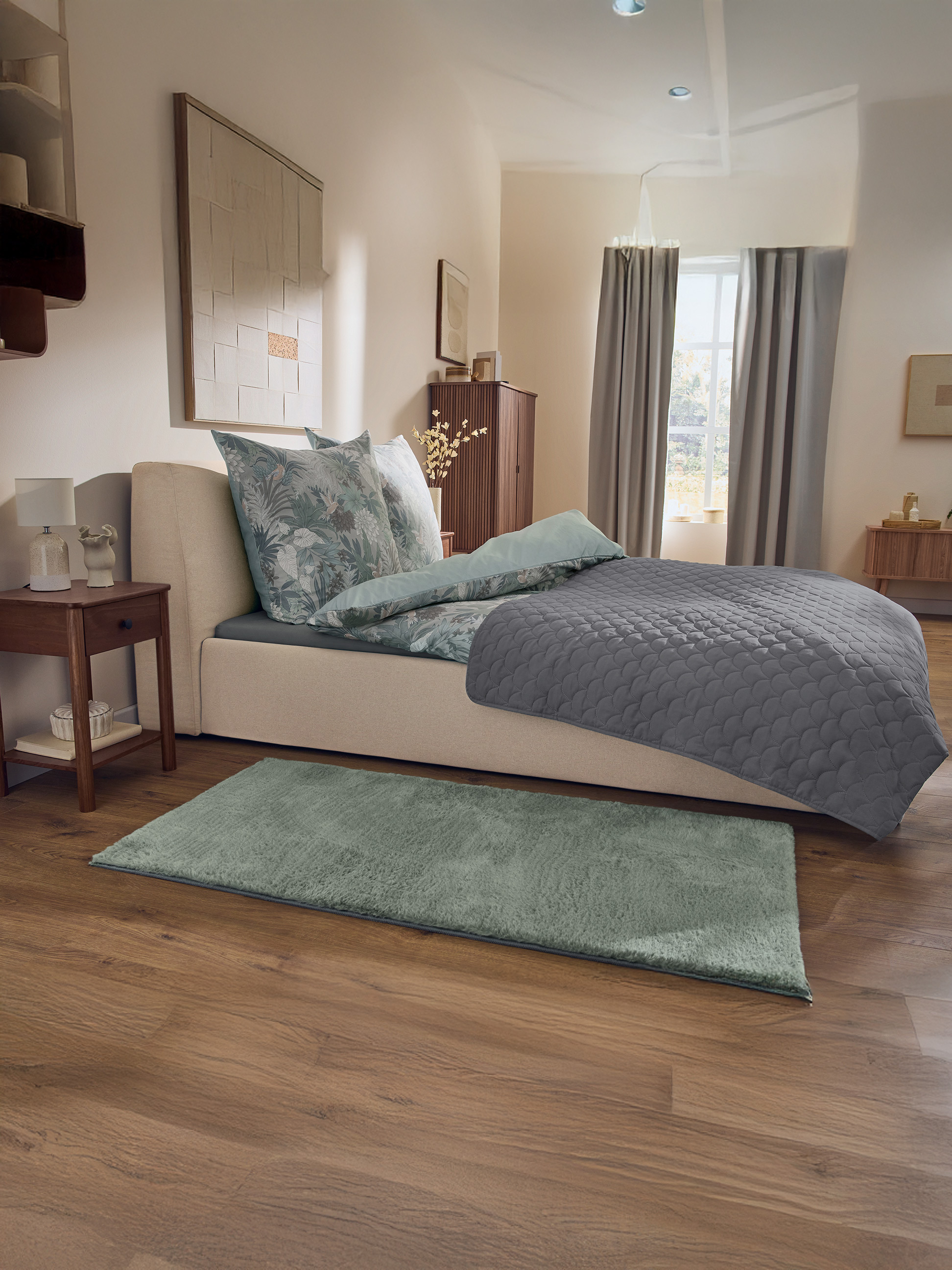Slaapkamer met beige bed, bloemig beddengoed, grijs sprei en groen vloerkleed