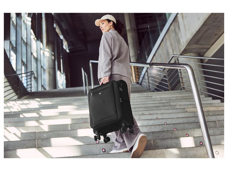 Een vrouw met een zwarte koffer met wielen loopt de trap op.