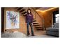 Meisje in een bordeauxrode hoodie met 'PARIS AMOUR CLUB' tekst en donkere jeans, staand in een moderne woonkamer.
