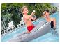 Jongen op haai-zwemband met waterpistool in zwembad met vrouw.
