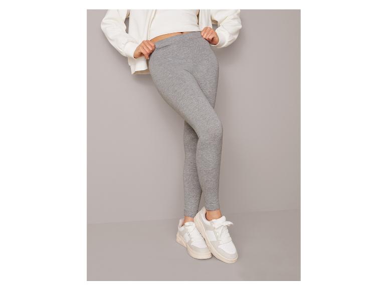 Grijze leggings en witte sneakers.