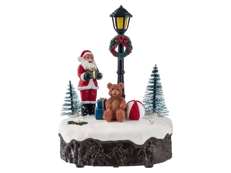 Kerstdecoratie met kerstman, teddybeer en lantaarnpaal op een besneeuwde basis.