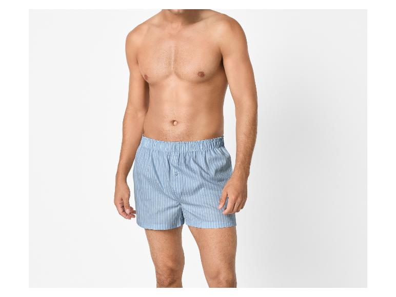 Man zonder shirt, gekleed in blauw gestreepte boxershorts.