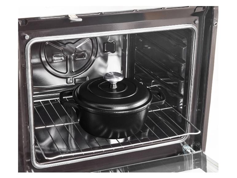 Zwarte gietijzeren pan met deksel in een oven.