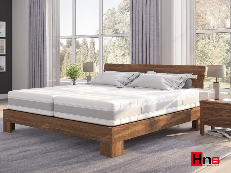 Een houten bedframe met een matras van Hnb Schlafsysteme.