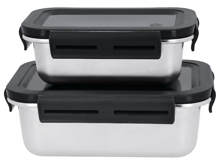 Twee roestvrijstalen voedselcontainers met zwarte deksels en sluitingen, gestapeld op een witte achtergrond.