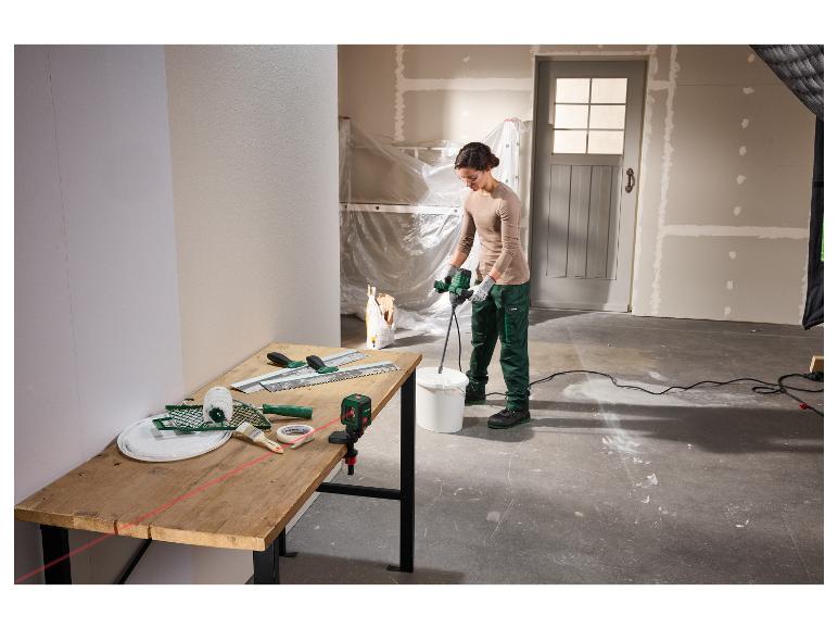 Vrouw mengt pleister met een mixer, gereedschap en laserwaterpas op een tafel in een kamer in renovatie.