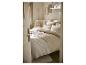 Lichte slaapkamer met een bed opgemaakt met beige en witte lakens en kussens.
