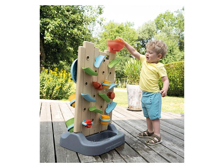 Een kind speelt met een Smoby waterspeelset: waterval en kleurrijke accessoires.