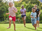 Kinderen rennen op blote voeten over een grasveld.