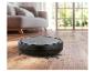 Robotstofzuiger op houten vloer met vuil, in een woonkamer.