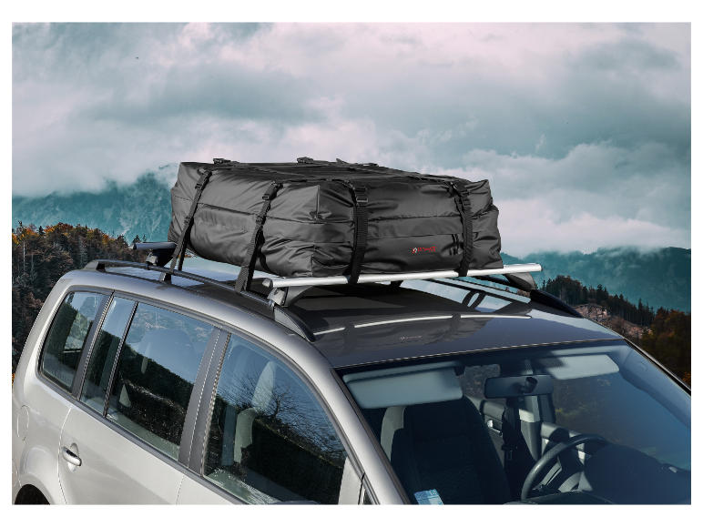 Een Ultimate Speed dakkoffer op een auto, met een bergachtig landschap op de achtergrond.